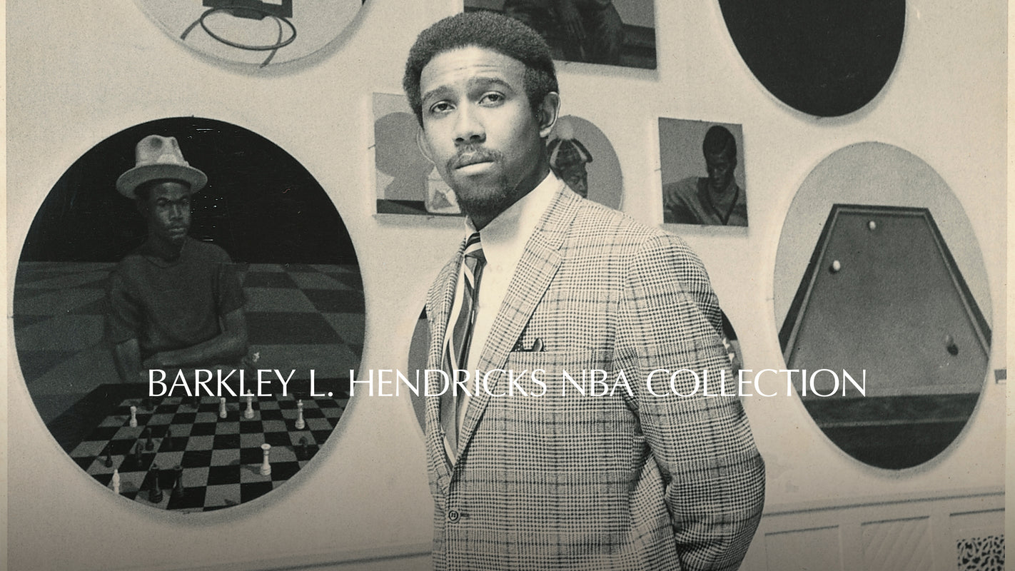 Man in a suit standing in front of circular portraits with 'Barkley L. Hendricks NBA Collection' text.