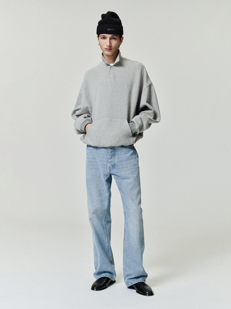 Person wearing a gray sweater and light blue jeans on a plain background